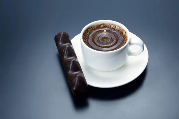 Gota de leche que cae en una taza blanca con café negro — Foto de Stock