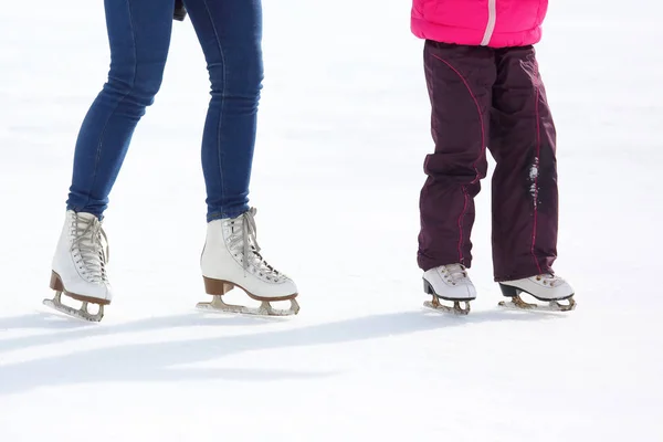 Bir yetişkin ve çocuk buz pistinde paten bacaklar — Stok fotoğraf