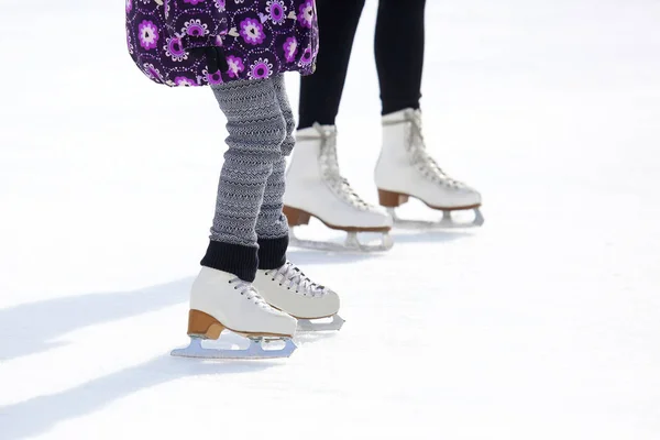 As pernas de um adulto e criança patinando na pista de gelo — Fotografia de Stock