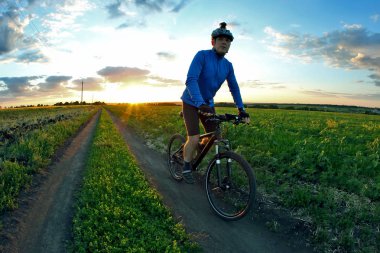 bisikletçi bir bisiklet ile günbatımında bir yolda gidiyor