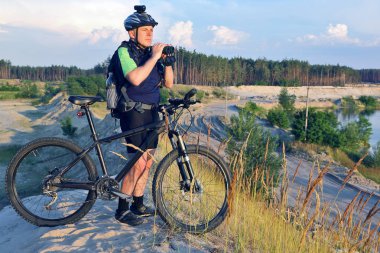 Bisikletçi bisiklet ve elinde dürbün ile standları bir 