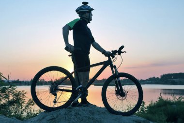gün batımında bisikleti ile ayakta bisikletçi silüeti