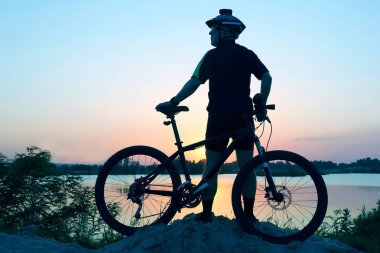 gün batımında bisikleti ile ayakta bisikletçi silüeti