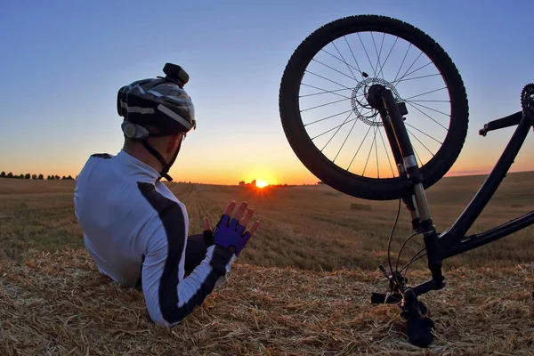 Spoczynku rowerzysta z rowerem wygląda o zachodzie słońca — Zdjęcie stockowe