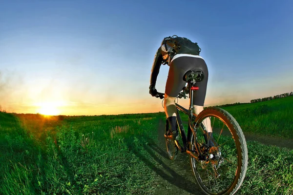 Radfahrer rast auf der Straße in den Sonnenuntergang — Stockfoto