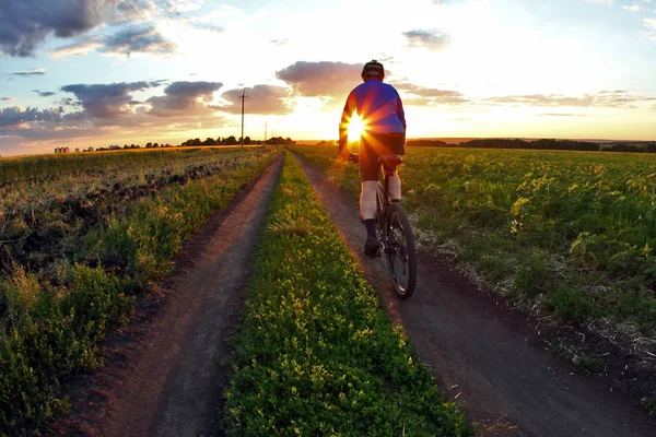 Radler fährt bei Sonnenuntergang mit dem Fahrrad auf einem Radweg — Stockfoto