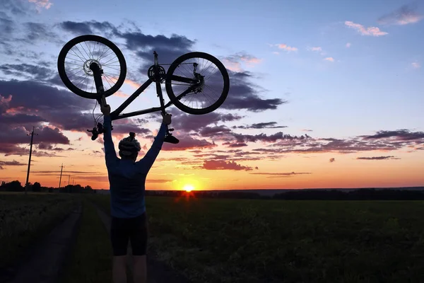 Silhouet van een fietser met armen opgewekt van de fiets bij zonsondergang — Stockfoto