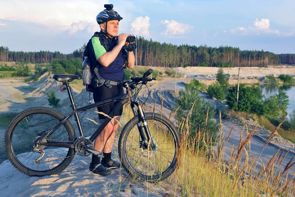 Bisikletçi bisiklet ve elinde dürbün ile standları bir 