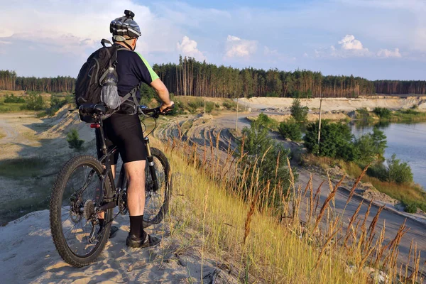 Bisikletçi bisiklet ile kumlu bir tepe üzerinde olduğunu