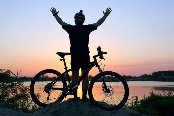 一站骑单车的双臂在日落时与一辆自行车引发的剪影 — 图库照片