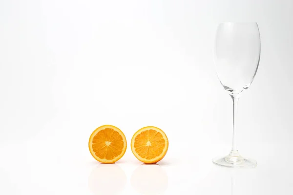 Скибочки апельсина і порожнє скло на білому тлі — стокове фото