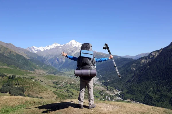 Турист с большим рюкзаком и поднятыми руками стоит перед горой — стоковое фото