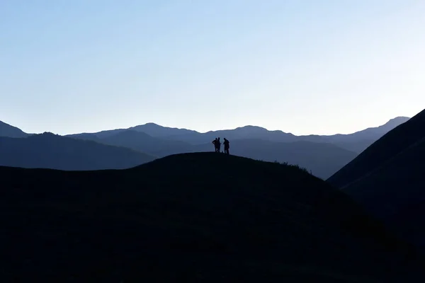 Silueta de personas de pie en la ladera — Foto de Stock
