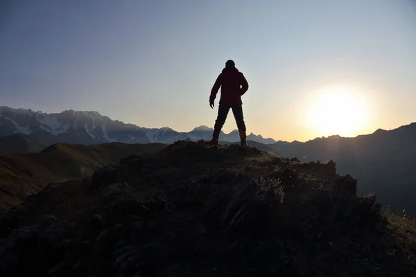Silhueta de homem em pé na montanha face ao nascer do sol — Fotografia de Stock
