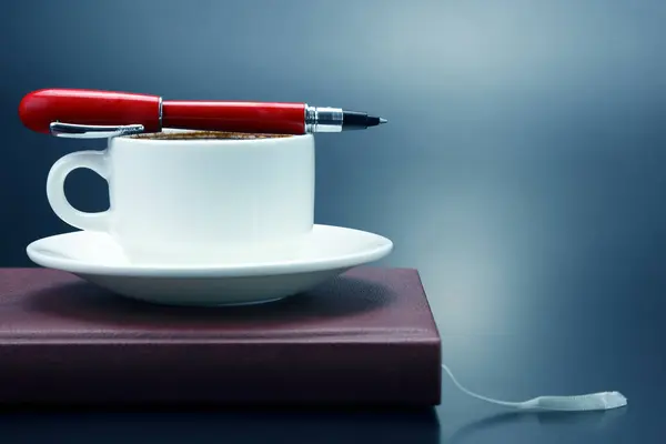 Красная ручка на белой чашке черного кофе — стоковое фото