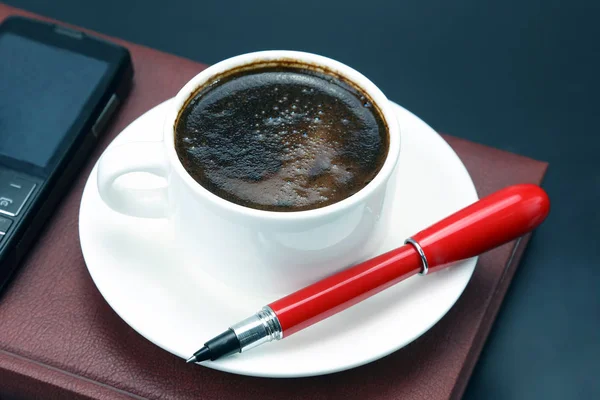 Pluma roja en una taza blanca de café negro —  Fotos de Stock