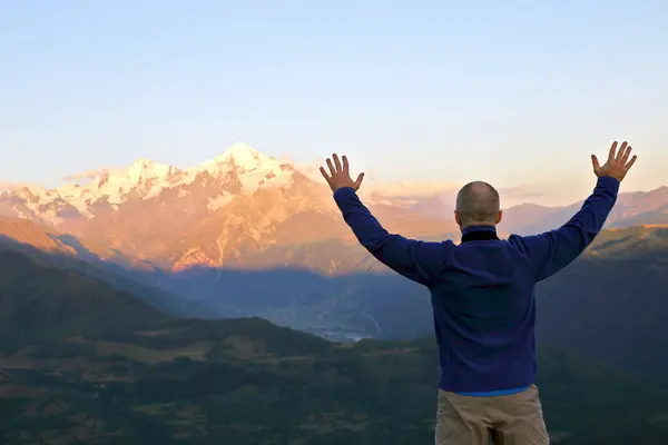 Man with and raised hands standing in front of the mountains Stock Image
