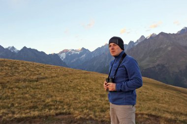 uzun yürüyüşe çıkan kimse dürbün ile dağlar bir arka plan üzerinde duruyor. Svaneti