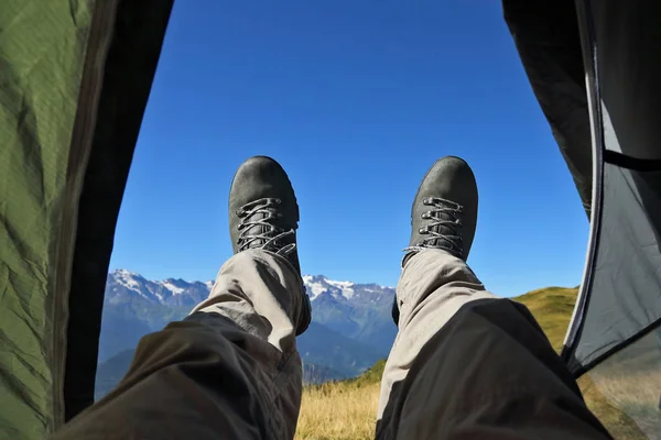 Нога туриста в сапогах из палатки с горами — стоковое фото
