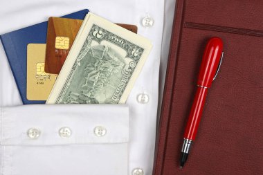 pasaport, para, kalem, defter ve banka kartları üzerinde beyaz bir gömlek vardır