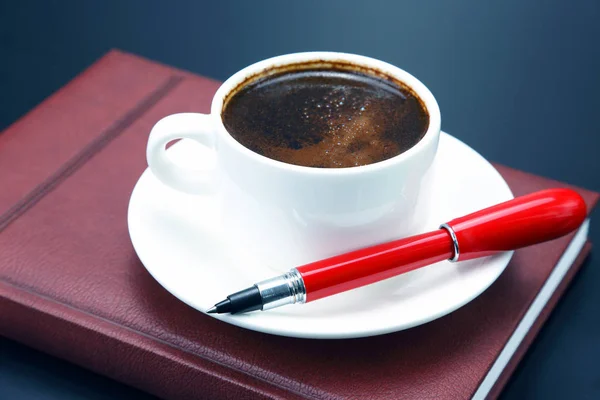 Penna rossa su una tazza bianca di caffè nero — Foto Stock