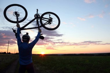 bir bisikletçi bisiklet kadar günbatımında kaldırdı kollarını silüeti