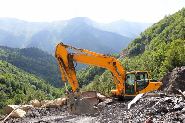 Excavadora que trabaja en la construcción de carreteras en terrenos montañosos — Foto de Stock