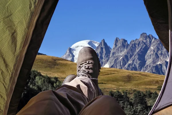 Нога туриста в сапогах из палатки с горами на заднем плане — стоковое фото