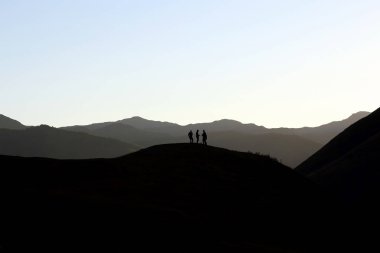 tepe üzerinde duran insanlar silüeti