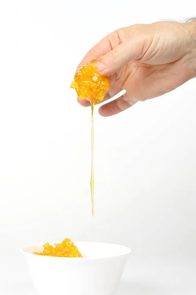 Honung från hand rinner ut i en vit plat — Stockfoto