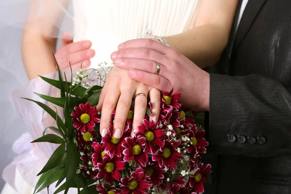 Mãos de noiva e noivo perto do buquê de casamento — Fotografia de Stock