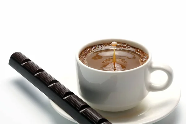 Капля молока, падающего в белую чашку с черным кофе — стоковое фото