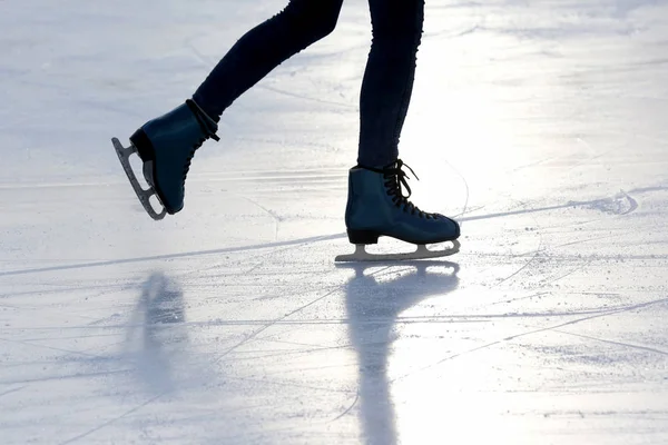 足を sunligh でスケート リンク上の氷スケートで滑る人 — ストック写真