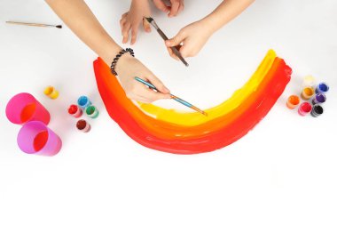 çocuğun elleri beyaz bir arka plan üzerinde bir gökkuşağı çizer