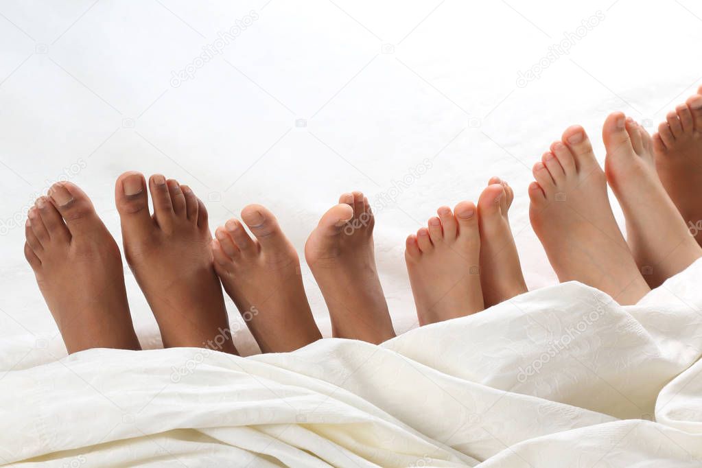 many children's feet peeking from under the blanket