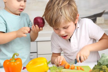 Çocuk havuç mutfak masasının üstünde kesmek.