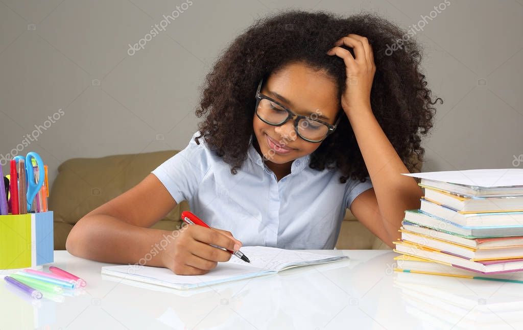 dark-skinned schoolgirl with glasses doing homewor