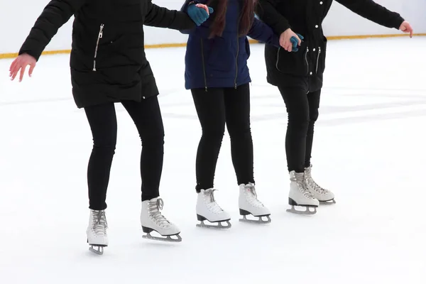 Drei Mädchen halten sich beim Schlittschuhlaufen auf der Eisbahn an den Händen — Stockfoto