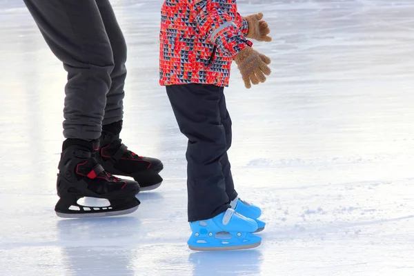 As pernas da criança e rinque de patinação no gelo adulto — Fotografia de Stock
