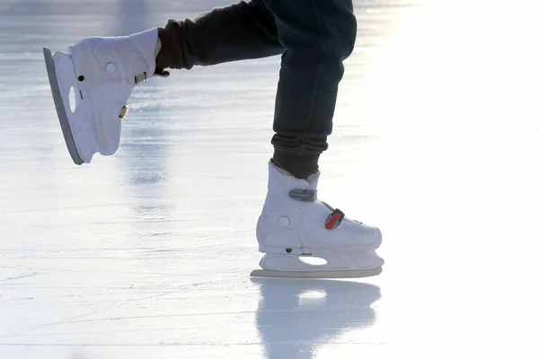 Füße auf den Schlittschuhen einer Person, die auf der Eisbahn rollt — Stockfoto