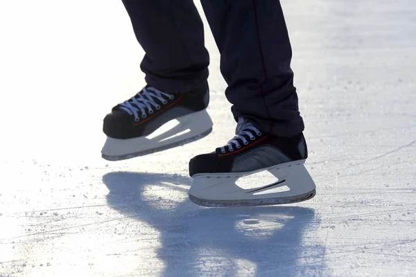 Füße auf den Schlittschuhen einer Person, die auf der Eisbahn rollt — Stockfoto