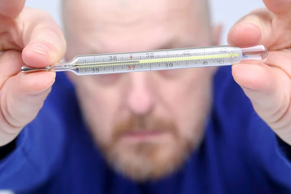 Hombre muestra un termómetro con una alta temperatura —  Fotos de Stock