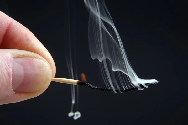 Spalování a kouření dřevěné zápas v ruce na temné poza — Stock fotografie