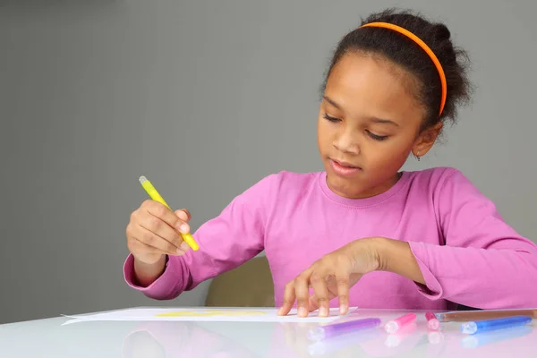 The girl draws a yellow pencil on white paper — Stock Photo, Image