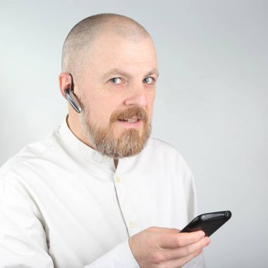 Sakallı bir cep telefonu ve Bluetooth ile hafif bir tişörtlü adam ben