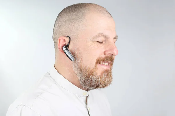 Bearded man in a light shirt with a Bluetooth in his ea — Stock Photo, Image