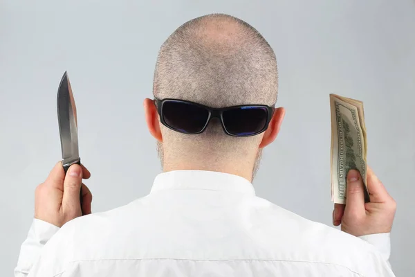Man stands with his back with money and a knife in his hand — Stock Photo, Image