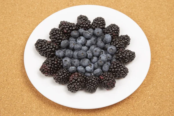 Blaubeeren und Brombeeren auf einem weißen Teller. Vitamin und Ernährung — Stockfoto
