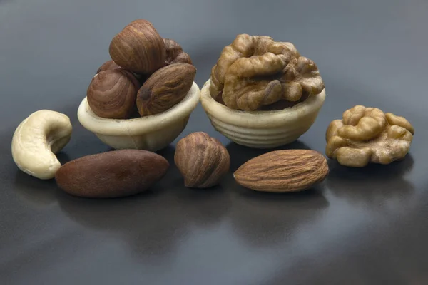 Different nuts in a waffle basket on a gray background. Vitamin — Stock Photo, Image