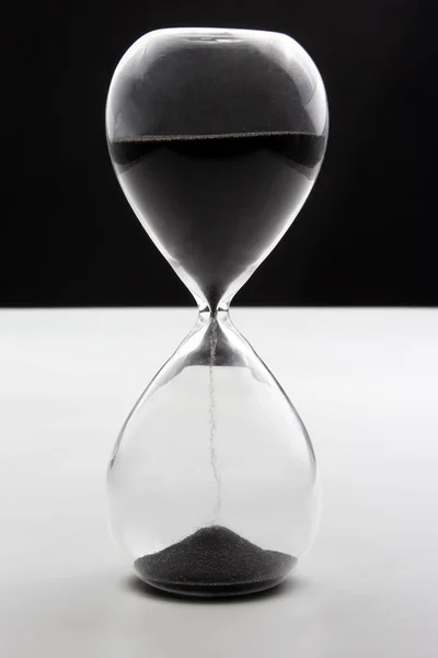 Reloj de arena sobre un fondo blanco oscuro. El tiempo es dinero. Negocio así — Foto de Stock